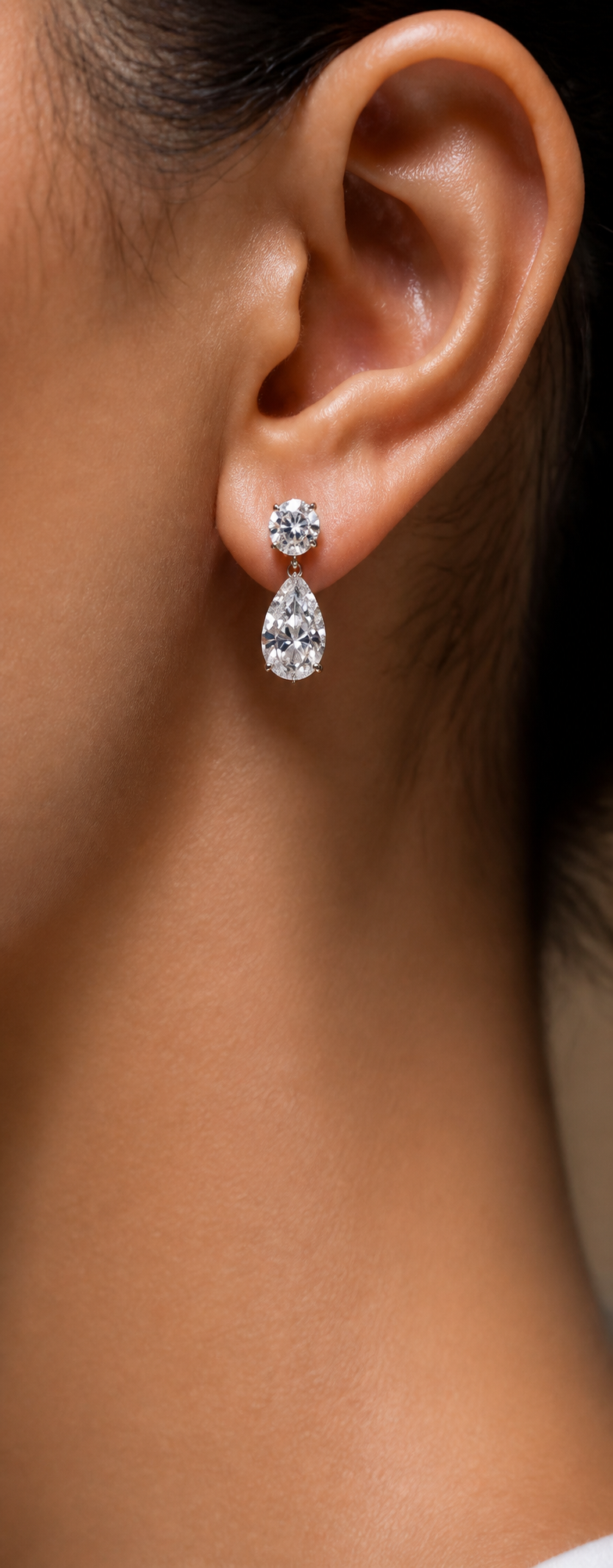 Model wearing diamond drop earring with round stud and pear-shaped diamond